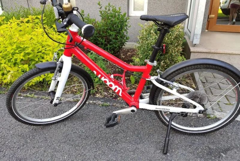 Dětské kolo Woom 4 v červené barvě s doplňky. 